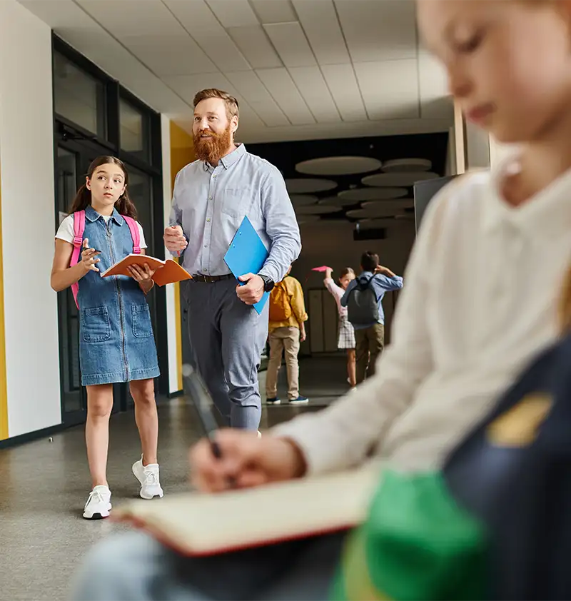Escena de vuelta al cole con profesor y alumnos en el pasillo del colegio.