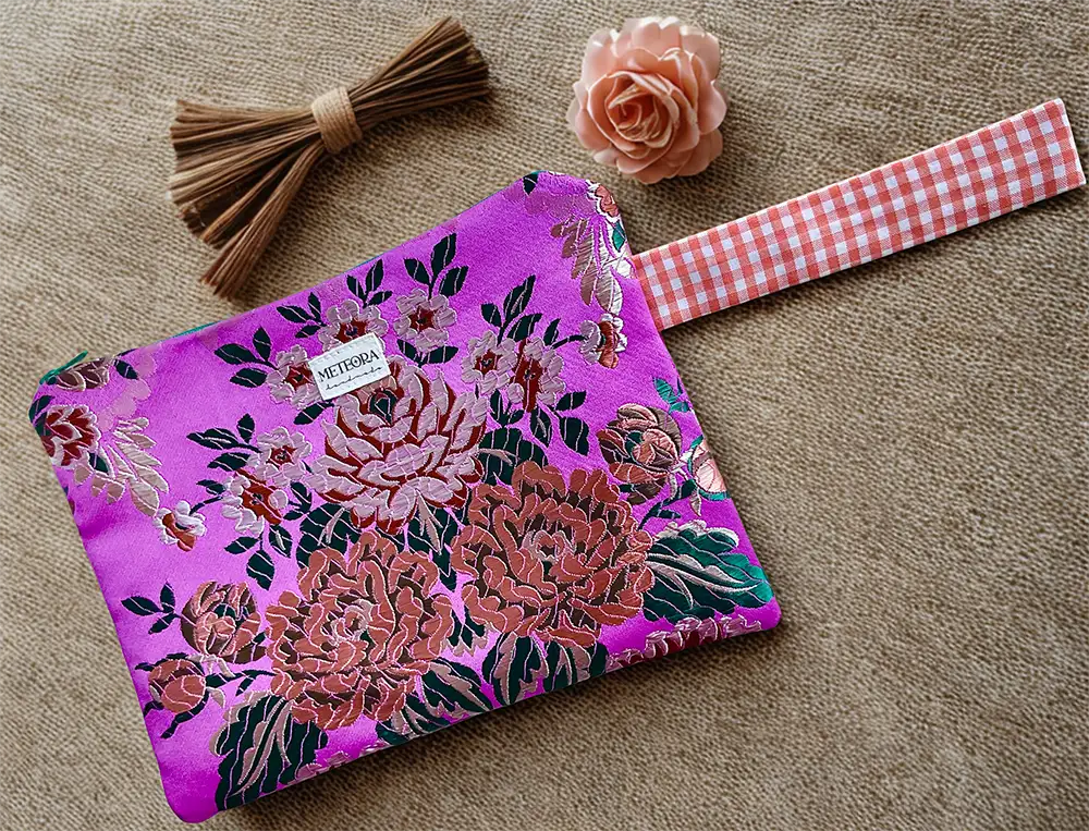 Neceser de tela fucsia con estampado floral en tonos rosados y marrones, hecho a mano por Meteora Handmade.